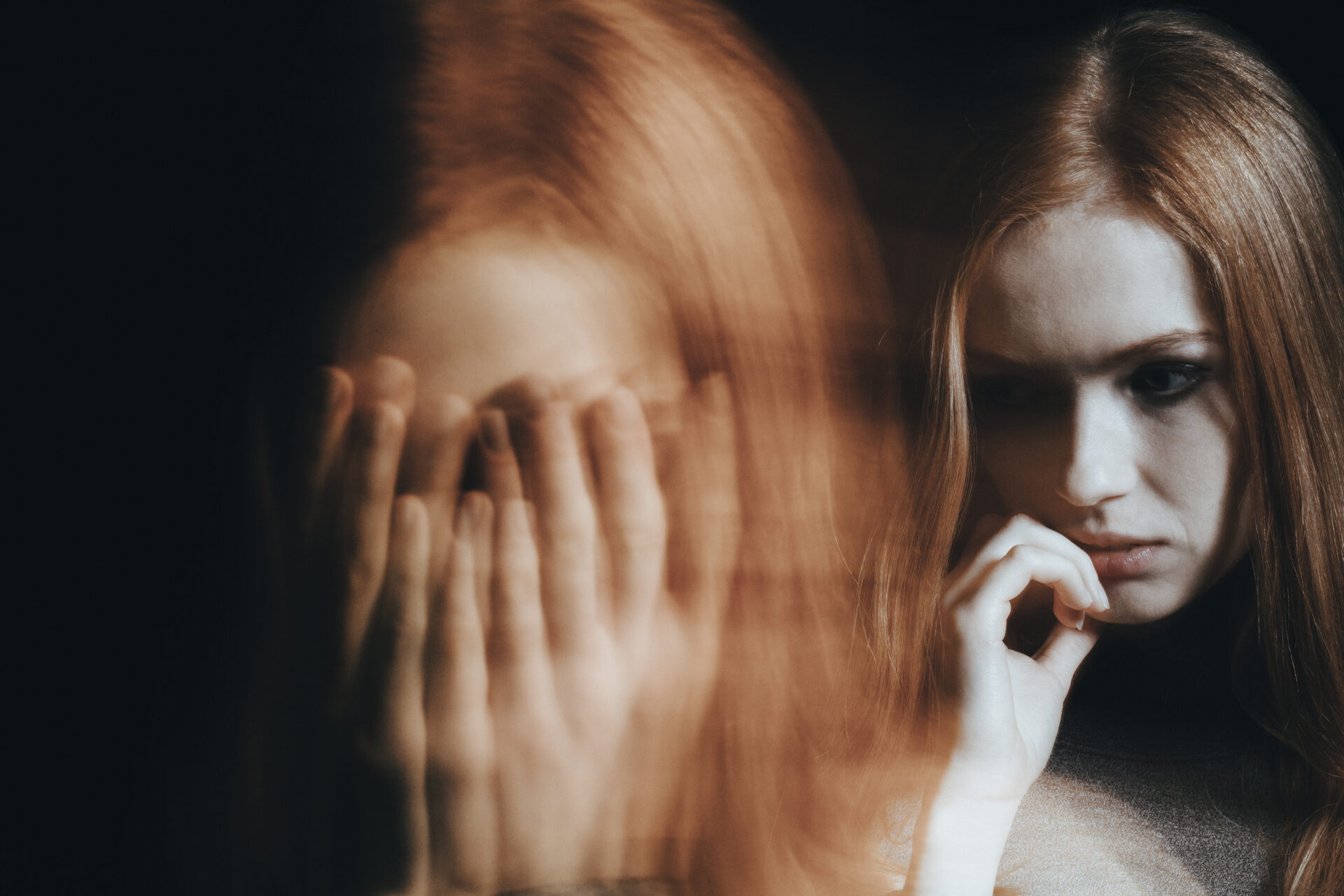 Close-up of a blurred face of a young girl with split personality disorder against black background