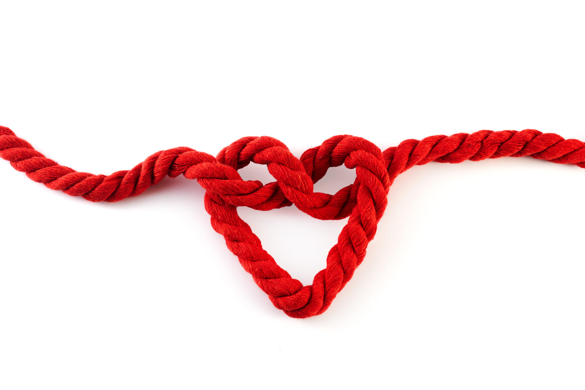 Red rope with a heart shaped knot isolated on white background to represent ligatures being used as a form of self-harm.