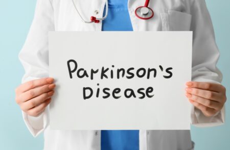 Doctor holds a sign saying 'Parkinson's Disease'
