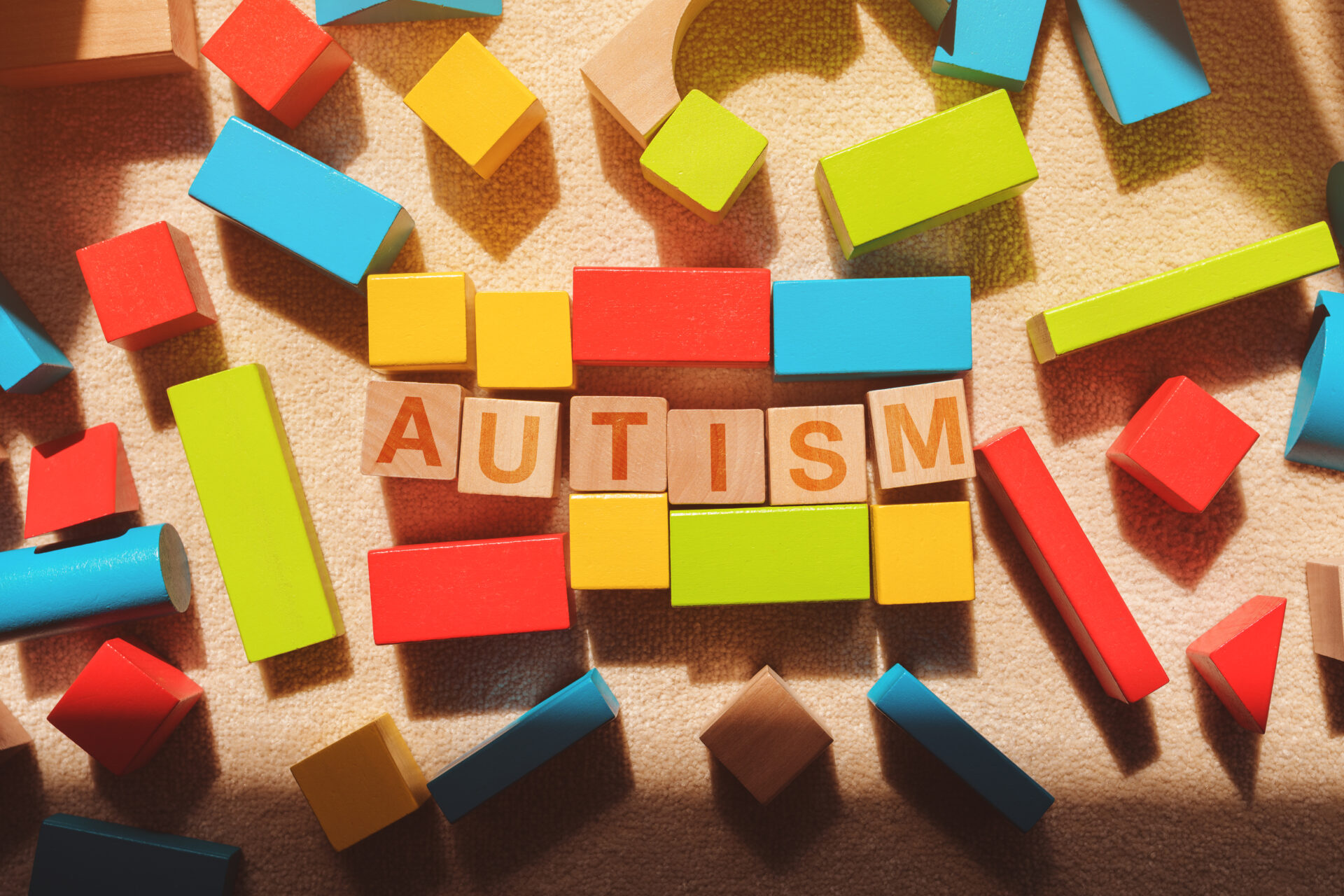 Using blue yellow and green building blocks around the word autism.